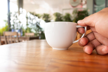 Fototapeta na wymiar Hand holding a hot coffee cup in coffee shop
