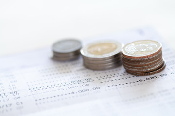 Selective focus of Thai's coins stacked over page of Bank account statement on  white background, Collecting money for investment concept with copy space