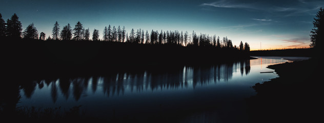 Mountain lake Oderteich at night with the torfhaus antenna mast and pine tree silhouettes and water reflection. Harz Mountain National Park in the german nature landscape