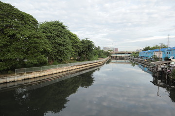 Fototapeta premium river in city have building, cuve and tree near water , on sky have white colud more.