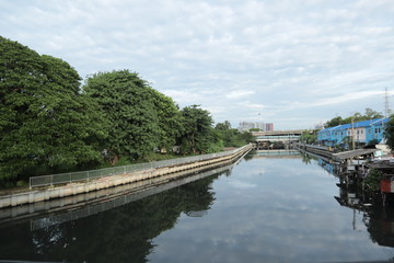 canal in city have building, cuve and tree near water , on sky have white colud more.