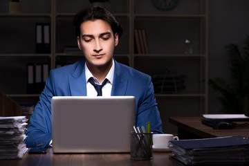 Young male employee working night in the office 