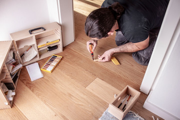 Handwerker bessert Fehlstellen im Parkett mit Reperaturset aus