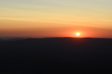 Fototapeta na wymiar Mountain panorama view with mountain silhouettes an sunset color tones. Harz National Park, Wolfswarte