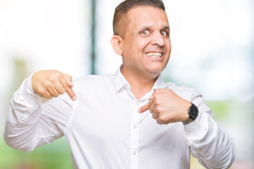 Middle age arab elegant man over isolated background looking confident with smile on face, pointing...