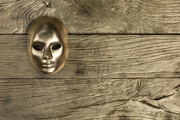 golden abstract mask on golden wooden background
