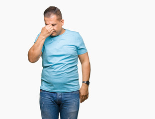 Middle age arab man wearing blue t-shirt over isolated background tired rubbing nose and eyes feeling fatigue and headache. Stress and frustration concept.