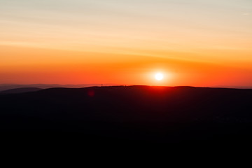 Mountain layer silhouettes after sunset with orange color tones. Harz National Park in Germany