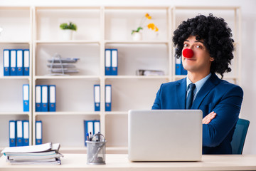Young clown businessman working in the office 