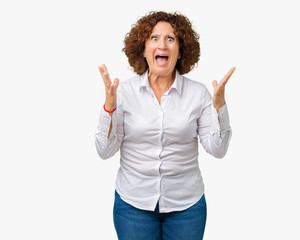 Beautiful middle ager senior businees woman over isolated background crazy and mad shouting and yelling with aggressive expression and arms raised. Frustration concept.