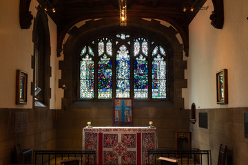 Indoor photo of a small church with lead glass windows and altar