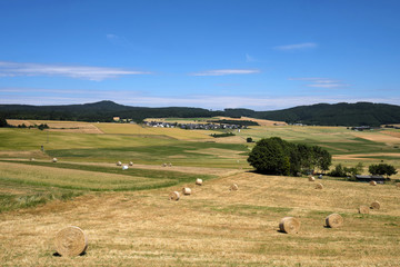 Strohballen und abgeerntete Felder in der Eifel und die Ortschaft Döttingen und die Hohe Acht - Stockfoto