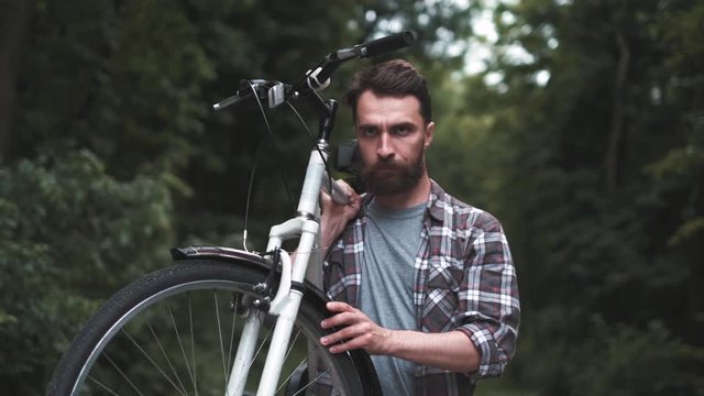 Brutal hipster guy in park carrying fixie bicycle