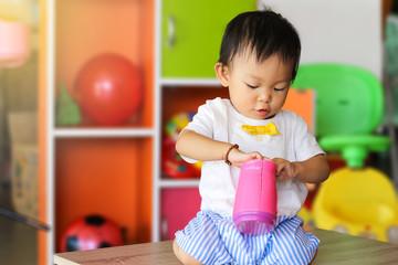 Learning and development of baby aged one year old. Happy asian child girl playing with many toys at the room.