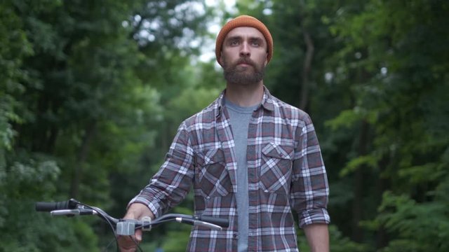 Brutal hipster guy in park carrying fixie bicycle