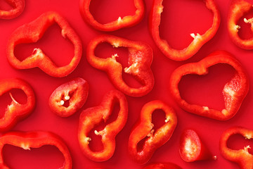 Paprika slices pattern on a red background viewed from above. Red pepper slices on a solid background. Top view
