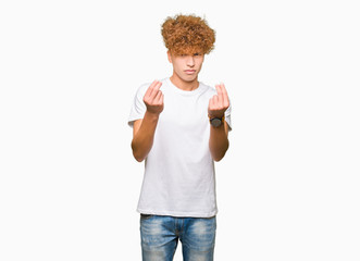 Young handsome man with afro hair wearing casual white t-shirt Doing money gesture with hand, asking for salary payment, millionaire business