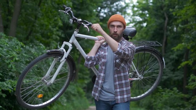 Brutal hipster guy in park carrying fixie bicycle