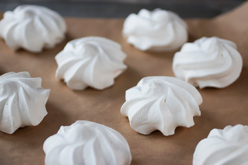 Fototapeta na wymiar White meringues on brown paper. Preparation for dessert Pavlova.