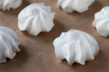 White meringues on brown paper. Preparation for dessert Pavlova.