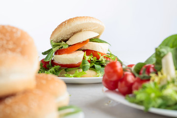 Sandwich with mozzarella, tomato and salad on the kitchen table.