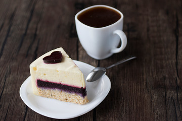 Gluten-free and sugar-free vegan cake on a white plate and white sashka coffee on a brown wooden table.