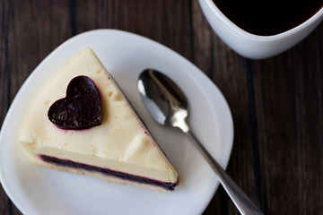 Gluten-free and sugar-free vegan cake on a white plate and white sashka coffee on a brown wooden table.