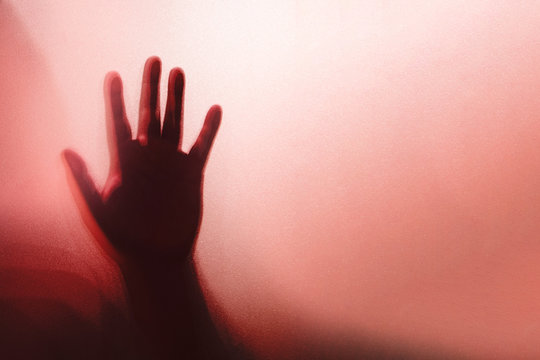 Shadow of the ghost hand behind frosted glass for horror concept