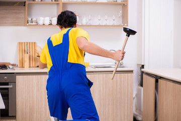 Young male contractor repairing tap at home 