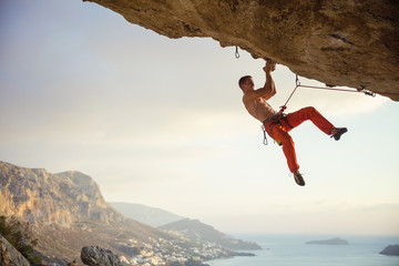 Young man climbing challenging route in cave