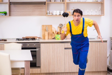 Young male contractor repairing tap at home 