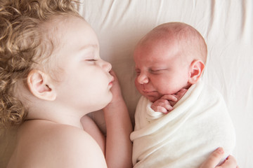Newborn baby sleeping next to his older brother little boy