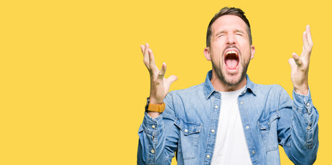 Handsome man with blue eyes and beard wearing denim jacket celebrating mad and crazy for success...