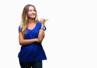 Young beautiful blonde woman over isolated background smiling with happy face looking and pointing to the side with thumb up.
