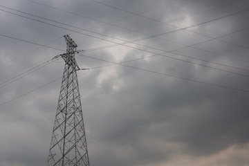 Close-up of large high-voltage electric towers and transmission lines before the storm