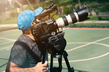 Blurry image of movie shooting or video production and film crew team with camera equipment at...