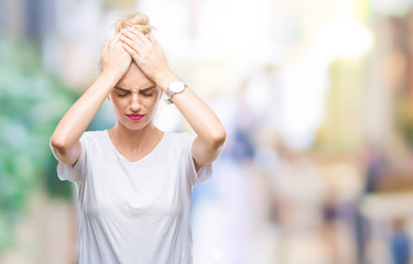 Young beautiful blonde woman wearing white t-shirt over isolated background suffering from headache desperate and stressed because pain and migraine. Hands on head.