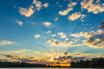 Sunset sky with dramatic clouds and the water surface of the river in the foreground