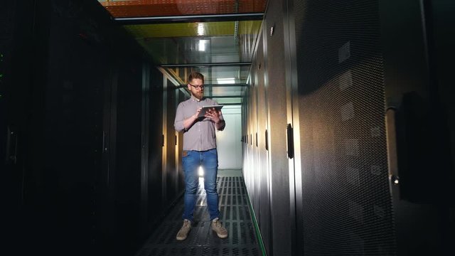 One programmer works at a data center, standing with a tablet.