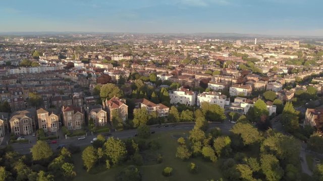 Aerial flyover green tree lined city streets of Bristol, England, drone shot at sunset  golden hour