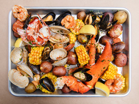 Clam bake with clams, crab legs, lobster claws, mussels, potatoes, corn and seasoning
