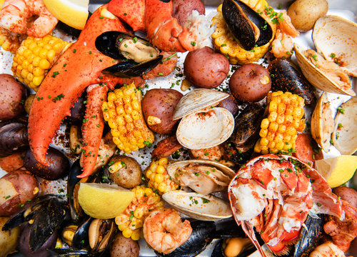 Clam bake with clams, crab legs, lobster claws, mussels, potatoes, corn and seasoning