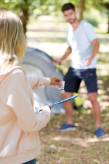 young couple playing badminton while on camping holiday