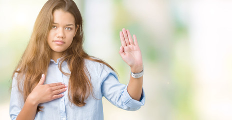 Young beautiful brunette business woman over isolated background Swearing with hand on chest and open palm, making a loyalty promise oath