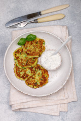Fritters of zucchini with fresh parsley and Basil. Delicatessen vegetable pancakes with sauce from sour cream and dill. Selective focus