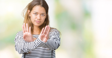 Fototapeta premium Young beautiful brunette woman wearing stripes sweater over isolated background Rejection expression crossing arms and palms doing negative sign, angry face