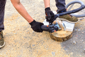 The worker cuts a metal plate and paving slabs for laying on the terrace with an angle grinder.