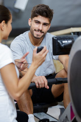 Fototapeta na wymiar personal trainer showing time on stopwatch to man in gym