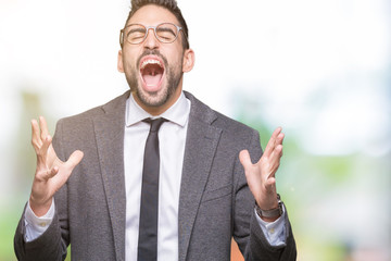 Young handsome business man over isolated background crazy and mad shouting and yelling with aggressive expression and arms raised. Frustration concept.