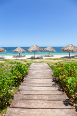 Beautiful view of a wooden path leading to the sandy beach on the Caribbean Sea in Cuba during a bright and sunny day.